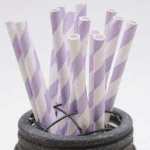 May include: A bunch of purple and white striped paper straws in a gray metal container.