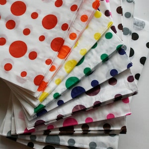Peut inclure: Une pile de papier de soie &agrave; pois color&eacute;s dans diff&eacute;rentes couleurs, dont le rouge, le jaune, le vert, le bleu, le marron, le rose et le gris.