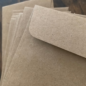 May include: A stack of brown kraft paper envelopes. The envelopes are folded and ready to be used for mailing.