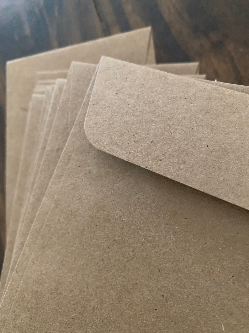 May include: A stack of brown kraft paper envelopes. The envelopes are folded and ready to be used for mailing.
