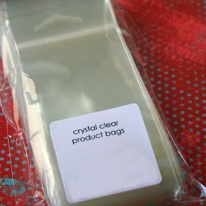May include: A stack of clear plastic bags with a white label that reads "crystal clear product bags".