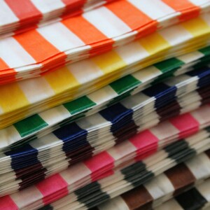 Peut inclure: Une pile de sacs en papier ray&eacute;s de couleurs vives en rouge, orange, jaune, vert, bleu, violet, rose, gris, marron et noir.
