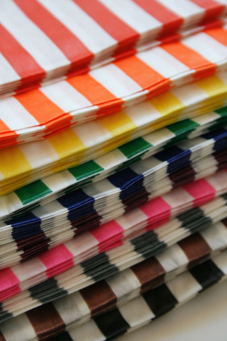 Peut inclure: Une pile de sacs en papier ray&eacute;s de couleurs vives en rouge, orange, jaune, vert, bleu, violet, rose, gris, marron et noir.
