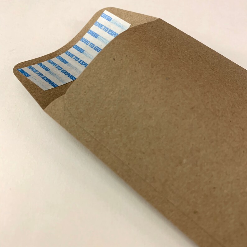以下が含まれることがあります： 白い粘着テープが貼られた茶色の紙の封筒。テープには「REMOVE TO EXPOSE」という文字が複数回繰り返されている。