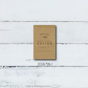 May include: A brown paper card with the text "JUNE 6, 2021" and "life" with a small leaf design. The text "SHELBY & ZACK GASTON" is below the date. The text "WIMBERLEY, TX" is below the names. The text "LET LOVE BLOOM." is below the location. The text "DESIGN MINI-C" is below the card.