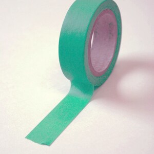 May include: A roll of green washi tape with a white background.