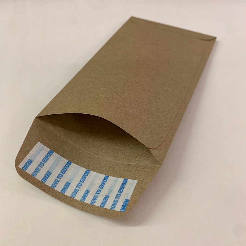 以下が含まれることがあります： REMOVE TO EXPOSEと書いてある青と白の粘着テープが付いた茶色の紙の封筒です。