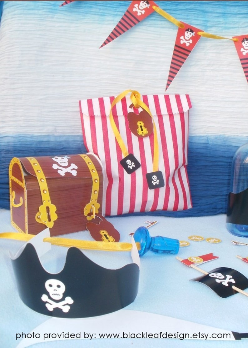 Peut inclure: Un ensemble de cadeaux de f&ecirc;te sur le th&egrave;me des pirates avec un sac en papier &agrave; rayures rouges et blanches, un coffre au tr&eacute;sor en carton marron, un chapeau de pirate noir et des pi&egrave;ces d'or. L'ensemble comprend &eacute;galement une bouteille en plastique bleue avec un bouchon et un petit drapeau avec un cr&acirc;ne et des os crois&eacute;s.