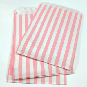 May include: Pink and white striped paper bags. The bags are folded and stacked on top of each other.