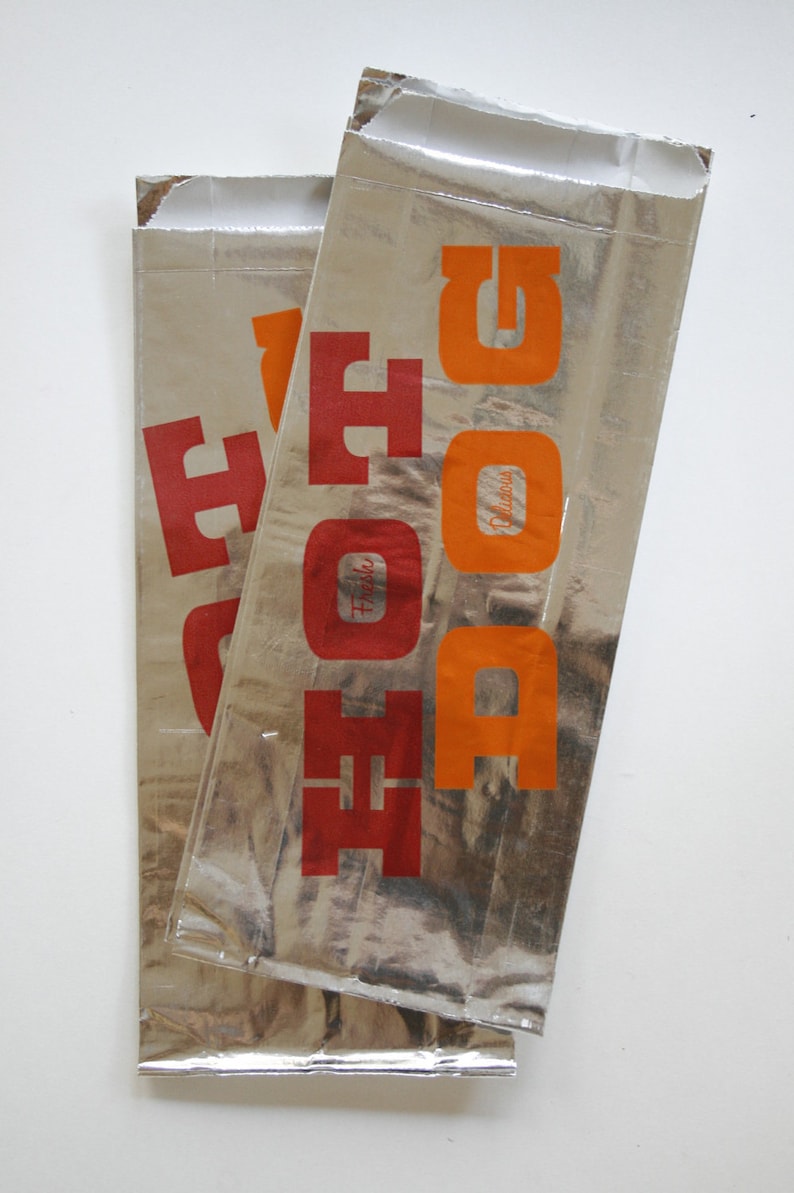 May include: Two silver foil food pouches with the word "FOOD" printed in red and orange letters. The text "Fresh" and "Delicious" are also printed on the pouches.