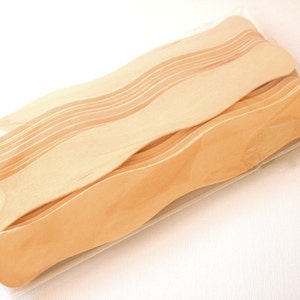 May include: A package of 12 unfinished wooden fan blanks. The fan blanks are light brown and have a wavy shape. They are packaged in a clear plastic bag.