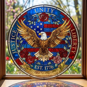 Puede incluir: Una vidriera redonda que representa un águila calva americana con las alas extendidas. El diseño incorpora la bandera estadounidense, rosas y las palabras "Unity, Justice, Liberty". También se incluye el texto "EST. 1776" y "The Miller Family".