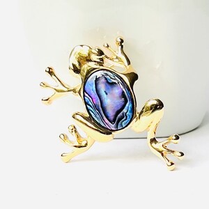 May include: A gold frog brooch with a blue, purple, and green abalone shell inlay.