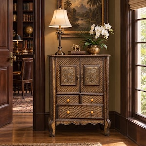 May include: A brown woven cabinet featuring two upper doors with embossed palm tree motifs, two small drawers, and one large bottom drawer, all accented with round wooden knobs and supported by curved legs with a textured finish.