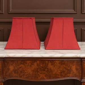 May include: A pair of matching red lamp shades with a square, tapered silhouette. Each shade features a structured fabric exterior with visible vertical seams along the four sides, creating a clean, geometric shape for a standard table lamp base.