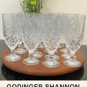 May include: Set of ten clear glass goblets with diamond and wheat pattern, displayed on a wooden tray. The goblets have a classic design, perfect for serving beverages. The image also shows yellow and green flowers.