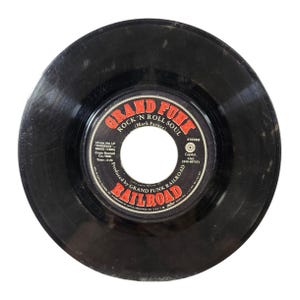 May include: A black vinyl record with a red and white label. The label features the text "GRAND FUNK RAILROAD" and "ROCK 'N ROLL SOUL (Mark Farner)".
