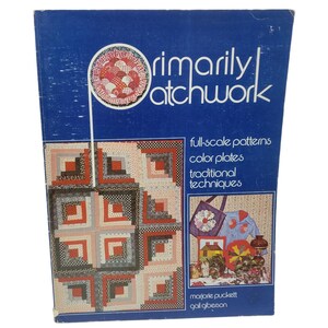 May include: A vintage book titled "Primarily Patchwork" with a blue cover. The cover features a patchwork design and the text "full-scale patterns, color plates, traditional techniques." The book is by Marjorie Puckett and Gail Giberson.