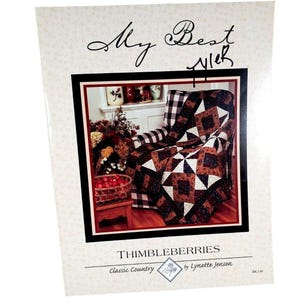 May include: A printed pattern for a quilt, featuring a cozy armchair draped with a patchwork quilt. The quilt has a starburst design in shades of brown, white, and navy. The text "My Best Ever" is handwritten at the top, with "Thimbleberries" at the bottom.