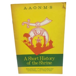 May include: A yellow booklet titled "A Short History of the Shrine." The cover features the text "A.A.O.N.M.S" at the top, with an orange and white emblem of a sword, star, and buildings. The bottom has the organization's name and address.