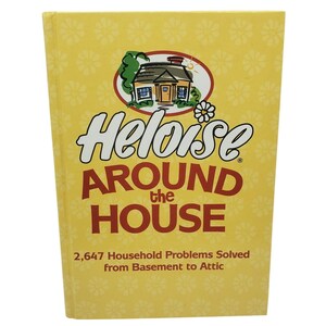 May include: A yellow hardcover book titled Heloise Around the House with a white flower pattern background. The cover features a small house illustration and the text 2,647 Household Problems Solved from Basement to Attic in brown font.