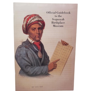May include: Official Guidebook to the Sequoyah Birthplace Museum. The cover features a portrait of a man wearing a red turban and holding a pipe. He is pointing at a board with letters. The text on the cover reads "Official Guidebook to the Sequoyah Birthplace Museum."