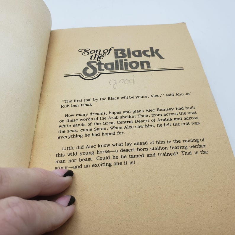 May include: Open book page featuring the title "Son of the Black Stallion" in a stylized font. The page has text and a handwritten "good" note. The paper is aged with a sepia tone.