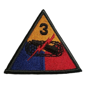May include: A triangular patch with a black border, a yellow background, and the number "3" in black. The patch features a red and blue design with a black tank and a red lightning bolt.