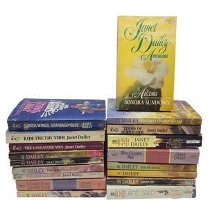 May include: A collection of vintage paperback books by Janet Dailey. The books have colorful covers with titles like "Silver Wings, Santiago Blue" and "Arizona Sonora Sundown." The books are stacked together, showcasing a variety of titles and designs.