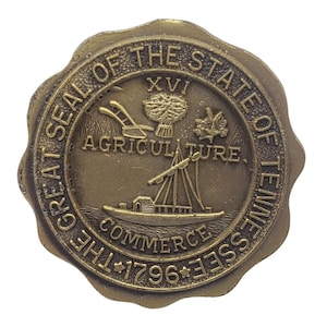 May include: A bronze-colored seal with the text "GREAT SEAL OF THE STATE OF TENNESSEE" encircling a central design. The design includes the words "AGRICULTURE" and "COMMERCE", a sailing ship, and the year "1796".