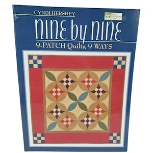 May include: A book titled "Nine by Nine" by Cyndi Hershey. The cover features a quilt design with red, tan, blue, and green geometric patterns. The text "9-Patch Quilts, 9 Ways" is also visible.