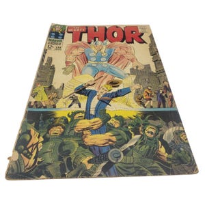 May include: A vintage comic book cover featuring Thor, the Mighty, in a red and blue costume, wielding a hammer. The cover also features a scene of Thor battling a group of monstrous creatures.
