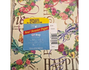 May include: A sheet of gift wrap with a floral design and the text "Happiness" in a gold script font. The wrap is cream colored with pink, purple, and blue flowers. The text "New! Heavier Paper" is on a red and white label with the words "Gift Wrap" and "Papel de Regalo".