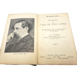 May include: Open book with the title "A Tale of Two Cities" by Charles Dickens. The left page features a portrait of Dickens, with the text "Charles Dickens, 1868." The right page displays the title and publisher information.