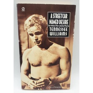 May include: A vintage paperback book cover for "A Streetcar Named Desire" by Tennessee Williams. The cover features a sepia-toned image of a shirtless man and the book's title in bold white text.