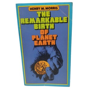 May include: A vintage book cover with the title "The Remarkable Birth of Planet Earth" in green and orange text. The cover features a blue background with a hand holding a golden globe. The author's name, Henry M. Morris, is at the top.