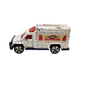 May include: White toy truck with red and blue accents. The truck has a sign on the side that says "WASHINGTON" with a planet logo.