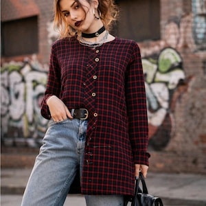 May include: A red and black plaid button-up shirt with long sleeves and gold buttons. The shirt is paired with light blue ripped jeans and a black belt. A black backpack is held in the hand.