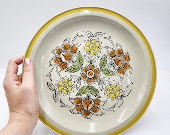 Plato redondo retro de cerámica Quasar de los años 70, estilo MCM, con flores naranjas y marrones.