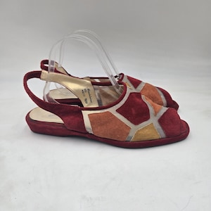 May include: A pair of Madelaine brand slingback sandals in size 9.5M, featuring a geometric patchwork design of suede panels in shades of deep red, burnt orange, and mustard yellow, accented with sheer mesh inserts and an open-toe construction.