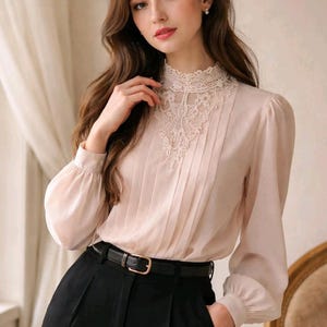 Könnte beinhalten: Eine hellrosa Bluse mit hohem, spitzenbesetztem Kragen und langen, gepufften Ärmeln. Die Bluse wird mit einer schwarzen, hoch taillierten Hose und einem schwarzen Gürtel mit goldener Schnalle kombiniert. Das Outfit ist elegant und klassisch.