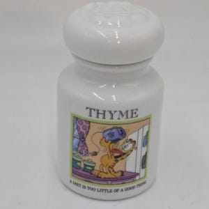 Może przedstawiać: Biały ceramiczny słoik na przyprawy z tymiankiem, z pokrywką. Słoik przedstawia ilustrację z kreskówki Garfield z napisem "THYME" nad obrazkiem i frazą "A DIET IS TOO LITTLE OF A GOOD THING" poniżej.