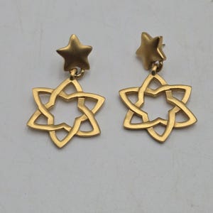May include: A pair of gold-toned dangle earrings featuring a star charm and a star-shaped openwork design.