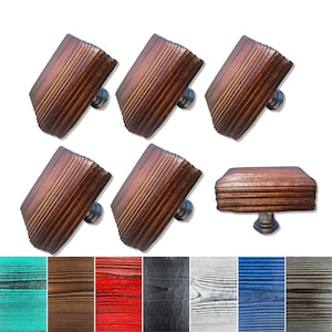 Peut inclure: Six boutons de porte en bois de forme carrée avec un dessus légèrement arrondi. Les boutons ont une finition en bois brun foncé avec un grain de bois et une vis en métal argenté. Les boutons sont disposés en deux rangées de trois. Sous les boutons se trouvent six échantillons de bois de différentes couleurs : turquoise, marron, rouge, noir, gris, bleu et marron.