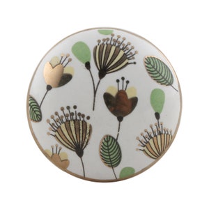 Peut inclure: Bouton de meuble rond en céramique blanche avec un motif floral. Les fleurs sont dans les tons de marron, jaune et or, avec des feuilles vertes. Le bouton a un bord doré et convient aux tiroirs ou aux armoires.
