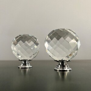 May include: Two clear crystal cabinet knobs with faceted surfaces and silver bases.
