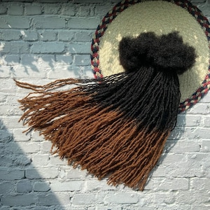 May include: Brown and black ombre dreadlocks hair extensions. The dreadlocks are long and thick, and they are arranged in a loose, flowing style.