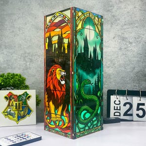May include: A rectangular lamp with stained glass panels. One panel shows a roaring lion, the other a green snake. The lamp has a Hogwarts crest and a remote control. The date on the calendar is December 25.