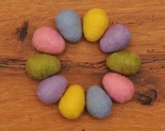 May include: A circle of nine felt Easter eggs in various colors, including pink, green, yellow, and blue, arranged on a wooden surface.