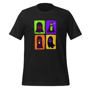 Puede incluir: Camiseta negra con un gráfico de cuatro fantasmas de dibujos animados en marcos cuadrados. Los fantasmas son de color verde, morado, naranja y amarillo, cada uno con una expresión única. Un diseño divertido y festivo para Halloween.